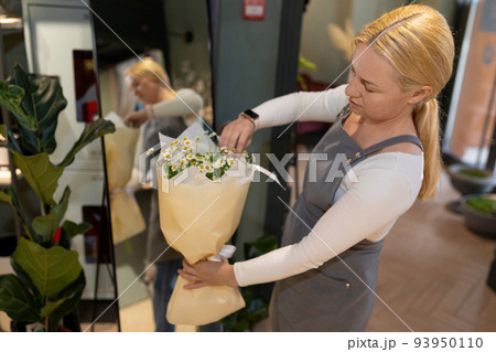 flower shop employee packing bouquets preparing his delivery to his client 93950110