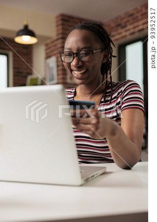 Happy shopaholic making purchase in internet store sale, holding credit card, online payment, electronic retail shopping. Smiling person buying products remotely using laptop, buyer paying for order 93952517
