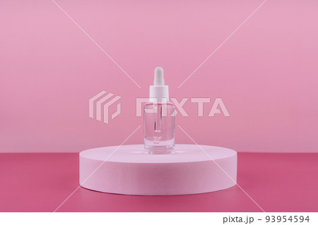 Serum cosmetic bottle with peptides and retinol on platform pedestal on pink background. Hyaluronic acid cosmetics transparent fashion product packaging with stylish props. Serum beauty dropper Serum cosmetic bottle with peptides and retinol on platform pedestal on pink background. Hyaluronic acid cosmetics transparent fashion product packaging with stylish props. Serum beauty dropper 93954594