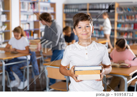 Boy with pile of books in library Boy with pile of books in library 93958712