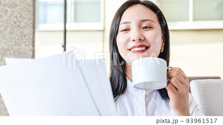 カフェでコーヒーを飲みながら仕事をする若い女性 93961517