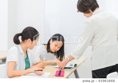 塾で先生に質問する小学生高学年の女の子と女性講師(日本人) 塾で先生に質問する小学生高学年の女の子と女性講師(日本人) 93963666