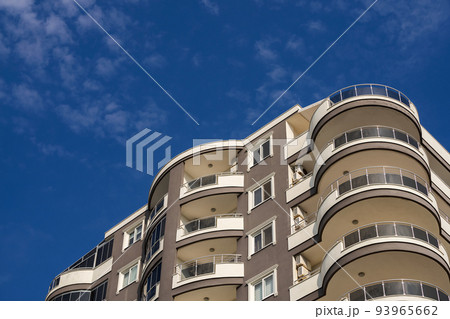 Exterior of a modern apartment building against a blue sky with clouds. 93965662