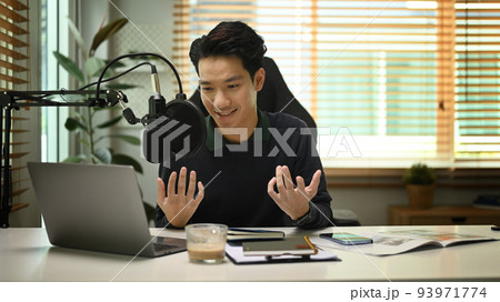 Asian man using laptop and microphone streaming audio podcast at home studio. Entertainment, podcasts and technology concept 93971774