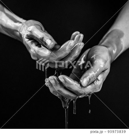 Women's hands in a viscous liquid similar to blood. Black and white photo. Women's hands in a viscous liquid similar to blood. Black and white photo. 93973839