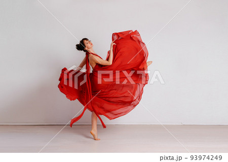 Dancer in a red flying dress. Woman ballerina dancing on a white studio background 93974249