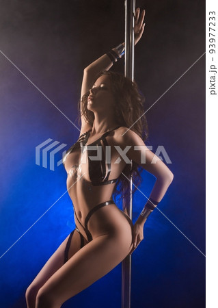 Sensual young woman dancing near pole in studio 93977233
