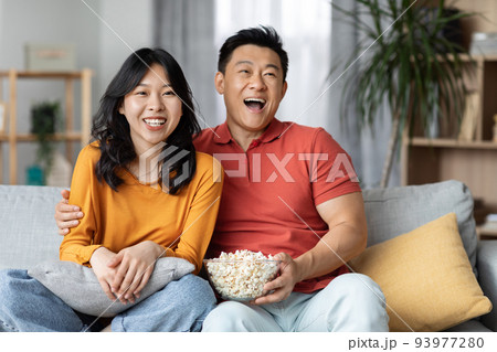 Cheerfy asian man and woman watching TV at home Cheerfy asian man and woman watching TV at home 93977280