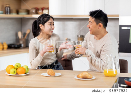 Happy asian spouses having fun while eating at kitchen Happy asian spouses having fun while eating at kitchen 93977925