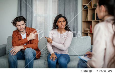 Offended sad millennial black female pointing finger at european man on meeting with psychologist Offended sad millennial black female pointing finger at european man on meeting with psychologist 93978189