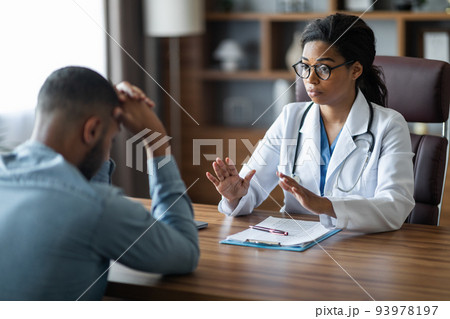 Black woman doctor consoling upset crying sick man patient Black woman doctor consoling upset crying sick man patient 93978197