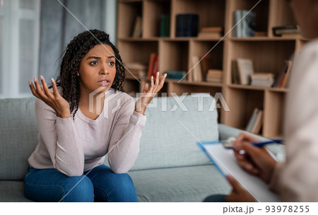 Psychotherapy. Despaired sad emotional young black woman looking at european doctor lady in office 93978255