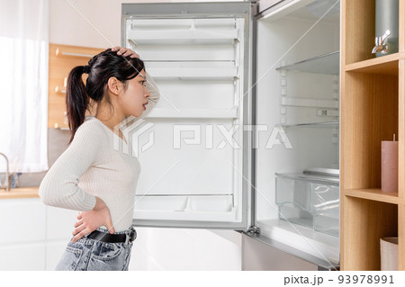 Overwhelmed young korean lady checking her fridge 93978991