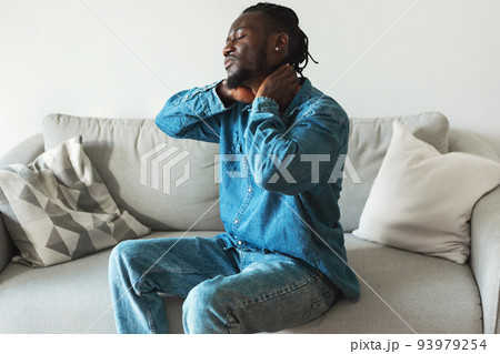 Unhappy African American Man Suffering From Neck Pain Sitting Indoor 93979254