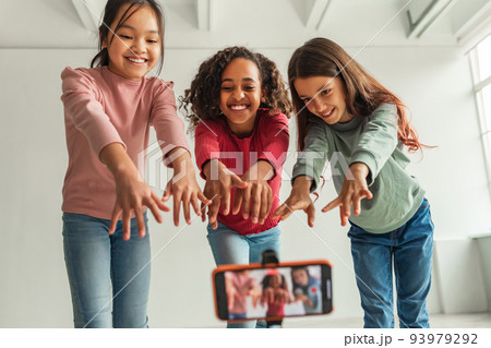 Three Multiethnic Blogger Girls Posing Making Video On Cellphone Indoors 93979292