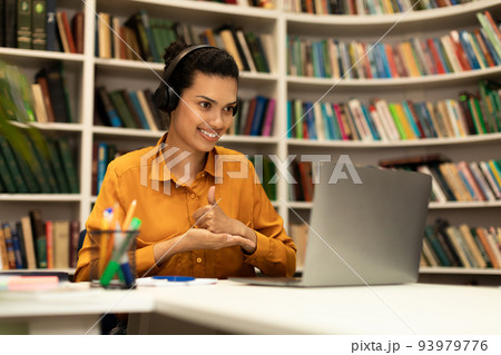 I like distance teaching. Happy mixed race female teacher gesturing thumb up, having online lesson via laptop 93979776