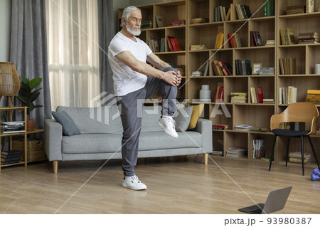 Athletic senior man doing workout at home, using laptop Athletic senior man doing workout at home, using laptop 93980387