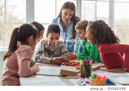Multiethnic School Kids And Teacher Using Smartphone In Modern Classroom 93980398
