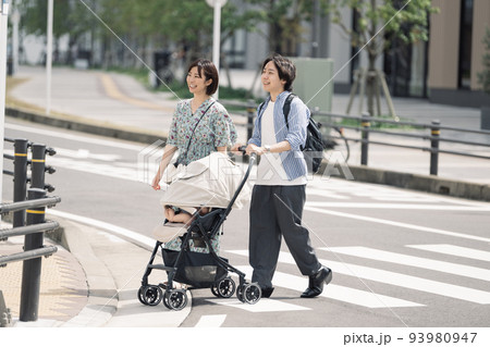横断歩道を渡る育児中の夫婦 横断歩道を渡る育児中の夫婦 93980947