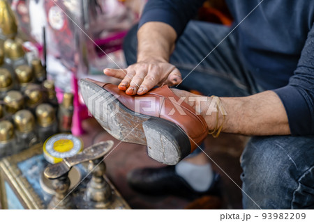 Ancient method of shoe cleaning with help of shoe polish. Man cleans shoes on street, close up. Ancient method of shoe cleaning with help of shoe polish. Man cleans shoes on street, close up. 93982209