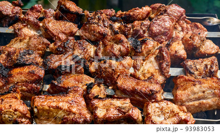 Delicious piece of meat fried over the fire at a picnic.  93983053