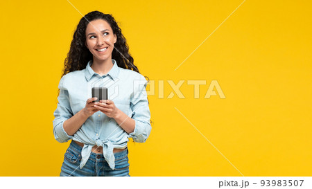 Cheerful Arabic Woman Using Mobile Phone On Yellow Background, Panorama Cheerful Arabic Woman Using Mobile Phone On Yellow Background, Panorama 93983507