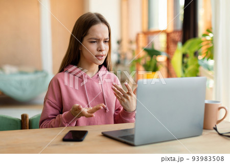 Smart teen girl video calling on pc laptop, talking and gesturing at computer webcamera, having video chat with teacher Smart teen girl video calling on pc laptop, talking and gesturing at computer webcamera, having video chat with teacher 93983508