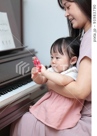 アップライトピアノを弾く1歳の女の子とママ 93983790