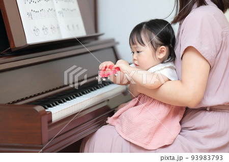 アップライトピアノを弾く1歳の女の子とママ 93983793