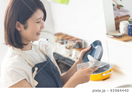 お皿を拭く笑顔の女性 93984440