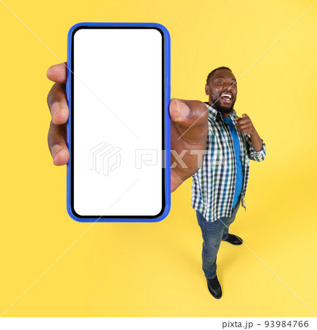 Cheerful Black Male Showing Huge Smartphone Over Yellow Background, Square Cheerful Black Male Showing Huge Smartphone Over Yellow Background, Square 93984766