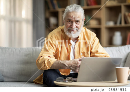 Senior man freelancer working from home, using laptop 93984951