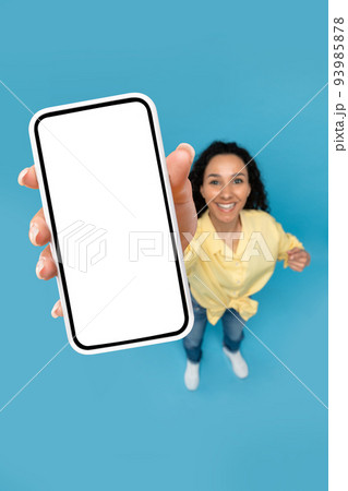 Above view of young woman pointing at mobile phone with blank screen, advertising website, offering space for ad mockup Above view of young woman pointing at mobile phone with blank screen, advertising website, offering space for ad mockup 93985878