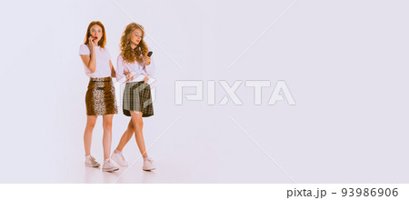 Portrait of beautiful young women with bright makeup walking, talking on phone isolated on grey background Portrait of beautiful young women with bright makeup walking, talking on phone isolated on grey background 93986906