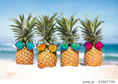 Pineapples in stylish sunglasses on the sandの写真素材