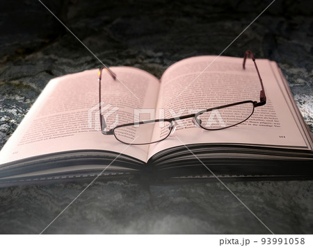 Opened book on a stone slab with an old used reading glasses between the pages with German text Opened book on a stone slab with an old used reading glasses between the pages with German text 93991058