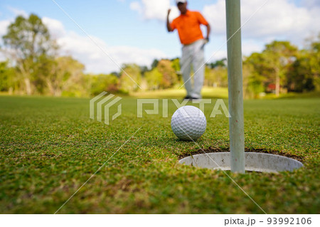 Golfer putting ball on the green golf, lens flare on sun set evening time. 93992106