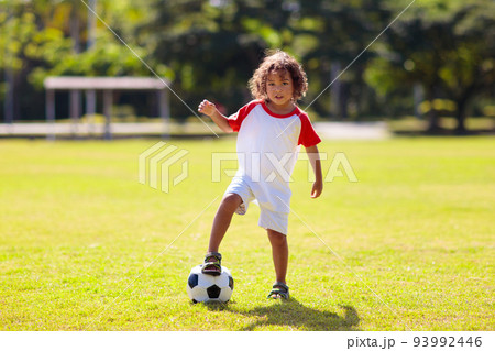 Cute curly little boy playing football. Kids play. 93992446