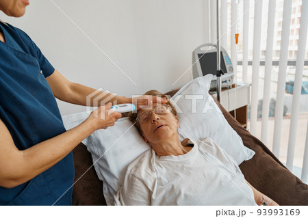 Close up of doctor measures patient's temperature with non-contact thermometer in hospital ward 93993169