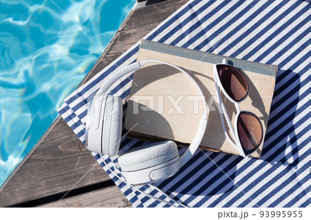 Book and headphones near swimming pool 93995955