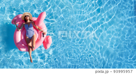 Woman relaxing on pink flamingo inflatable ring 93995957