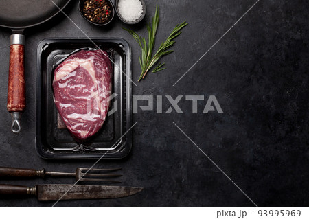 Vacuum packed beef steak. Ribeye steak and cooking utensils 93995969