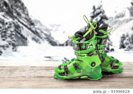 ski boots on a wooden table against the background of mountains. bright green sports ski boots ski boots on a wooden table against the background of mountains. bright green sports ski boots 93996628