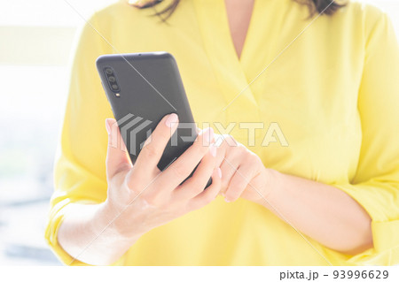 Close up of women's hands holding cellphone smartphone. Woman use of cellphone. Indoor. Close up of women's hands holding cellphone smartphone. Woman use of cellphone. Indoor. 93996629
