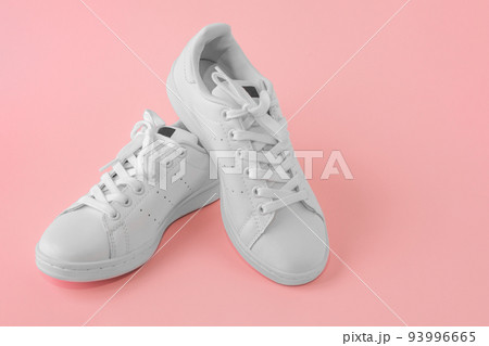 Pair of new white sneakers on pink background. New white leather sneakers, sports shoes. Copyspace 93996665