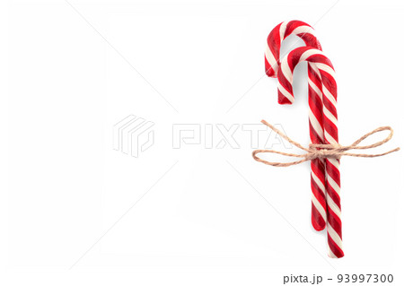 Closeup of two candy canes with twine bow isolated on white. copyspace. Minimal composition with peppermint candies. Top view Closeup of two candy canes with twine bow isolated on white. copyspace. Minimal composition with peppermint candies. Top view 93997300