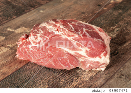 RAW meat on dark wooden background. Raw meat piece of pork on rustic wooden background is ready for cooking. RAW meat on dark wooden background. Raw meat piece of pork on rustic wooden background is ready for cooking. 93997471