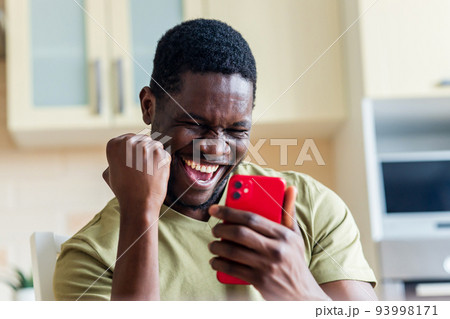 happy afro american man winner excited by mobile app with joy 93998171