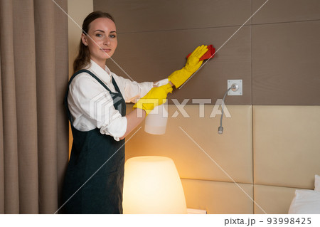 Hotel maid in rubber gloves uses detergent to clean room Hotel maid in rubber gloves uses detergent to clean room 93998425