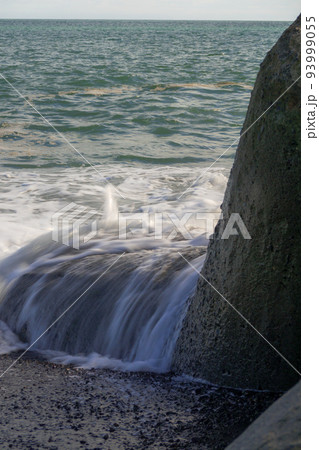 静岡 広野海岸にあるテトラポットに乗りかかる波の写真素材